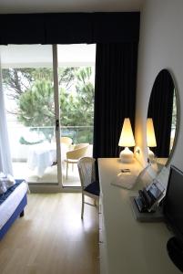 a bedroom with a desk with a laptop and a mirror at Hotel Luxor in Rimini