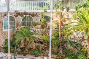 a greenhouse with palm trees and a stone wall at Monaco/Beausoleil I : Luxury Apartment 1BR vue Mer in Beausoleil