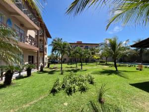 een groene tuin met palmbomen en een gebouw bij Flat Praia da Taíba - com vista Mar in Taíba