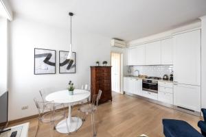 a white kitchen with a white table and chairs at [BOCCONI] Elegante Appartamento con WIFI in Milan