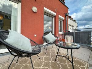 un patio avec deux chaises et une table sur un balcon dans l'établissement Appartio - modern - luxuriös - Netflix - Flughafennähe - 55 qm, à Leura