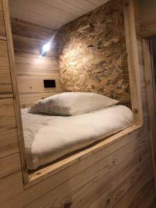 Ce lit se trouve dans un dortoir doté d'un mur en pierre. dans l'établissement Studio Beethoven, à Lans-en-Vercors