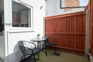 a patio with chairs and a table and a window at Wonderful Townhouse with BBQ Backyard in Great Yarmouth