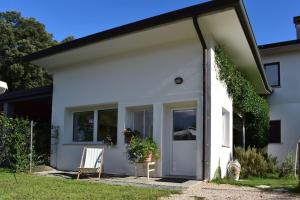 uma casa branca com uma porta e uma cadeira em Open space Villa Miani em Silea