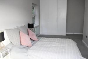 a white bed with pink pillows in a bedroom at Superb New Build 2 Bed Flat - 6 Ophelia Court in Epsom