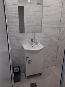 Apartment Cozy Home 3 في روس: حمام أبيض مع حوض ومرآة