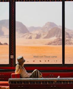 une femme assise sur un banc qui regarde le désert depuis un train dans l'établissement Wadi Rum Travel camp, à Wadi Rum