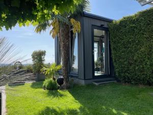 a black house with a palm tree in the yard at BEACHHOUSE mit Alpen- Stadt- und Poolblick , WLAN in Passau