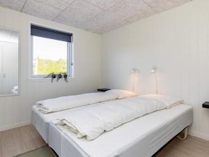 two beds in a white room with a window at Holiday home Læsø II in Læsø