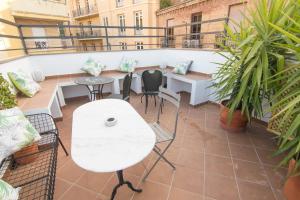 balcón con mesa blanca, sillas y plantas en tuGuest Gran Vía Apartments, en Granada