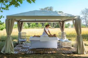 a woman sitting on a bed under a gazebo at Château de Fonscolombe in Le Puy-Sainte-Réparade