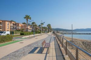 ławka na chodniku obok plaży w obiekcie Appartement Cavalaire sur Mer w mieście Cavalaire-sur-Mer