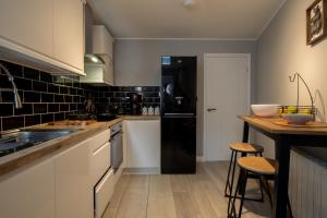 a kitchen with white cabinets and a black refrigerator at Gorgeous House with BBQ Patio in Great Yarmouth