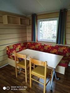 a room with a table and two chairs and a couch at Mobil home au bord du lac in Nages