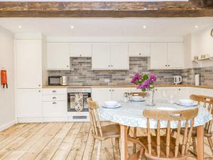 uma cozinha com armários brancos e uma mesa com flores em Bunts Barn em Okehampton