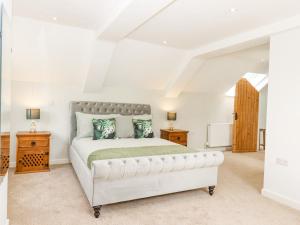 um quarto com uma grande cama branca com almofadas verdes em Bunts Barn em Okehampton