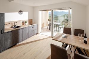 a kitchen and dining room with a table and a balcony at Prälatenhof Wine & Apartments in Caldaro