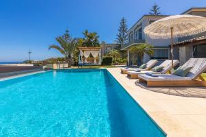 una piscina con tumbonas y sombrilla en Villa Ioulia Gouves, en Gouves