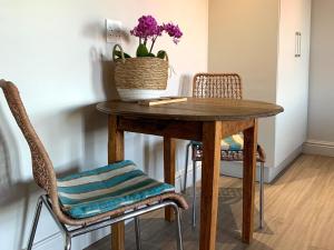 une table avec deux chaises et un vase avec des fleurs violettes dans l'établissement Hermanus Waterfront Apartment, à Hermanus