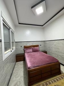 - une chambre avec un lit et une couverture violette dans l'établissement Bel Appartement 1er Étage confortable près de la plage - spécialement pour familles, à Saïdia