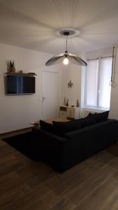 a living room with a black couch and a ceiling at Appartement cosy centre ville in Roanne
