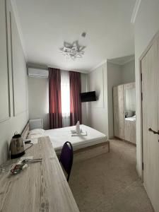 a room with a bed and a table and a window at Hotel Bereke in Atyraū