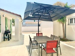 CAPUCINE Jolie maison proche Plage في لا كوردي سور مير: طاولة وكراسي مع مظلة زرقاء على الفناء