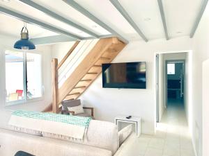 a living room with a couch and a flat screen tv at CAPUCINE Jolie maison proche Plage in La Couarde-sur-Mer
