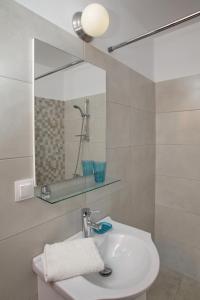 a white bathroom with a sink and a mirror at Finikas Apartments in Skopelos Town