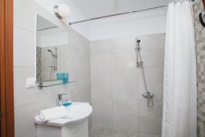 a white bathroom with a sink and a shower at Finikas Apartments in Skopelos Town
