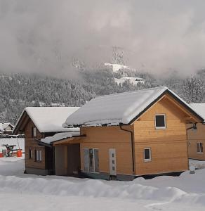 ein schneebedecktes Haus mit einem Berg im Hintergrund in der Unterkunft Felsenfest Cottage in Kötschach