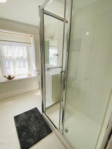 a glass shower in a bathroom with a rug at Shell Cottage Traditional Cottage Easton in Portland