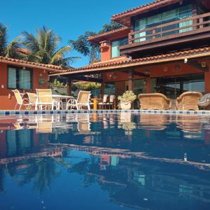 a resort with a swimming pool with chairs and a house at Pousada Bella Vista Geribá in Búzios