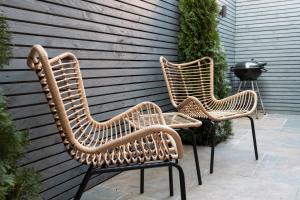 three wicker chairs sitting next to a wall at Cozy House with Modern Garden in Great Yarmouth