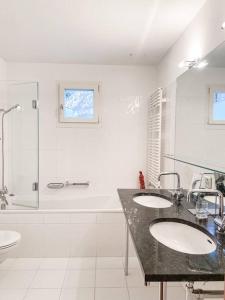een witte badkamer met 2 wastafels en een douche bij 4 1/2 Room Maisonette Apartment with great views in Sils Maria