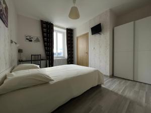 a bedroom with a large white bed and a television at Auberge du Château in Bouloire