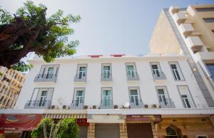 a white building with balconies on a street at Hôtel Olympic in Fez
