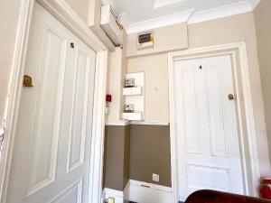 a hallway with a white door and a red chair at The Beverley Apartments London - Victoria in London