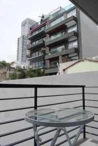 una mesa de cristal en un balcón con un edificio en STUDIO Fitz Roy - By HART en Buenos Aires