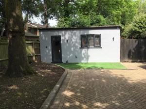 a small white house with a tree in a yard at Furze Cottages in Buckinghamshire