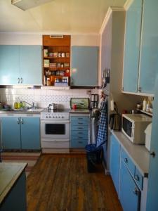 a kitchen with blue cabinets and a white stove at Guesthouse Simolle in Hammarstrand