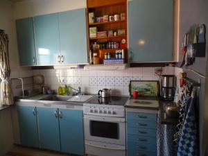 a kitchen with blue cabinets and a white stove top oven at Guesthouse Simolle in Hammarstrand
