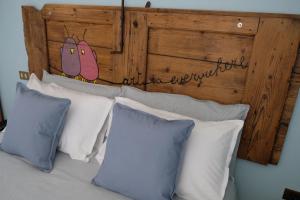 - un lit avec des oreillers blancs et une tête de lit en bois dans l'établissement ADRIA ART APARTMENTS 1, à Adria