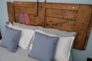 a bed with white pillows and a wooden headboard at Adria Art Apartments 1 in Adria