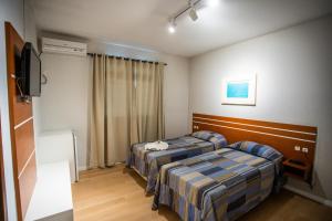 a hotel room with two beds and a television at Hotel Raul's in Gaspar