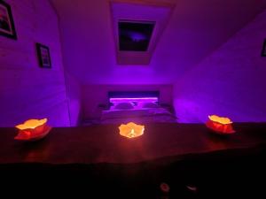Una habitación morada con una cama con dos velas encima. en Haut Doubs Plaisir, SPA, en Chamesol