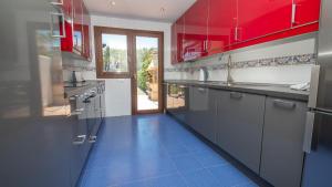 cocina con armarios rojos y suelo de baldosa azul en La Borboleta 8, en Manilva