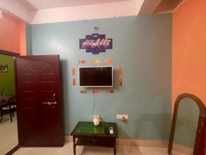 Habitación con puerta y TV en la pared en Veda Homestay en Agartala