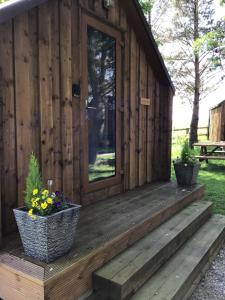 a wooden cabin with a porch with flowers on it at Cow Close Camping Pods in Leyburn