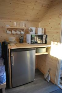 a kitchen with a counter with a refrigerator and a microwave at Cow Close Camping Pods in Leyburn